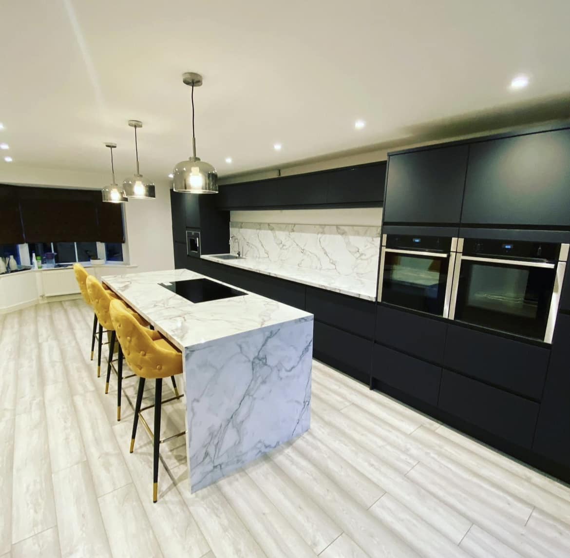 Modern kitchen with black cabinetry, marble island, and pendant lights.